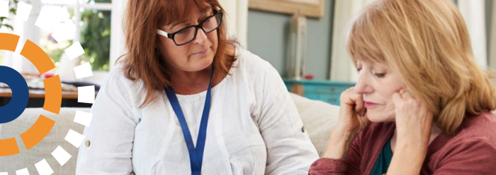 A woman with a lanyard around her neck sitting next to another woman with her head in her hands. 