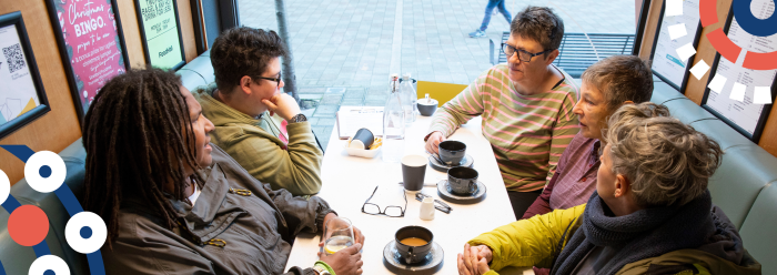 A group of people sat in a cafe having a drink talking